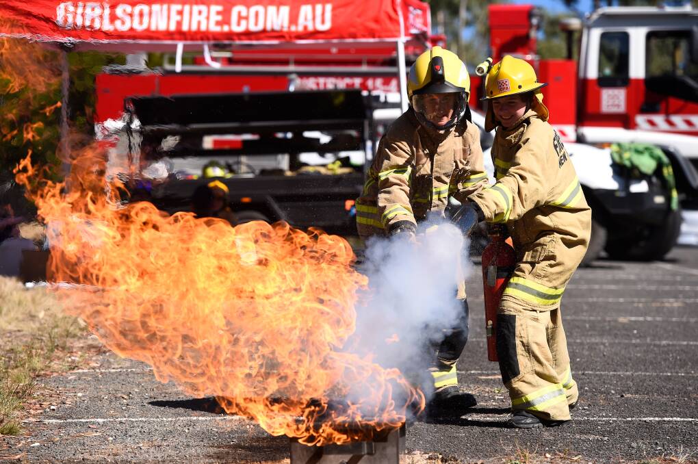 Tori Alexandrow works with Phoebe Wilson to extinguish a blaze at Creswick during a program to introduce girls aged 14-18 to emergency services work. Photo by Adam Trafford.