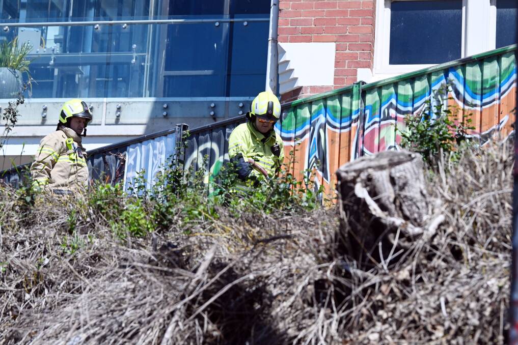 Firefighters work on the blaze, behind a Camp Street government building. The steep slope and narrow winding laneway made access challenging. Picture by Kate Healy.