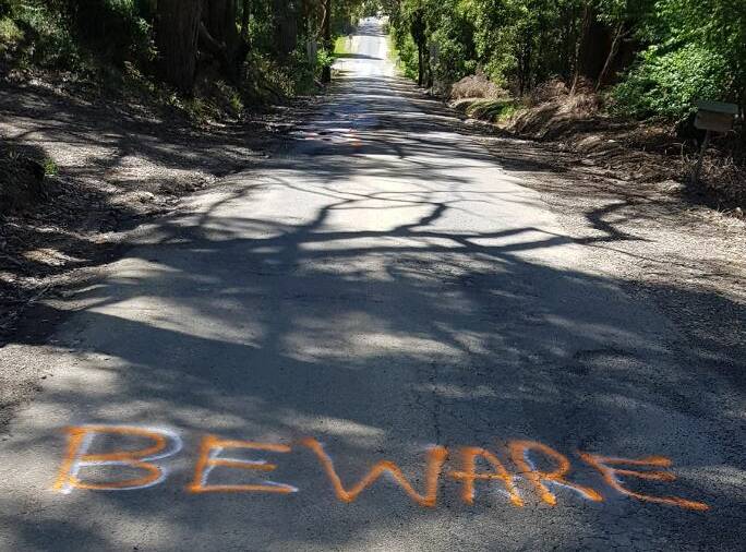 Locals have painted potholes - and safety messages - on a road that passes over the Western Freeway at Gordon. Picture from Facebook.