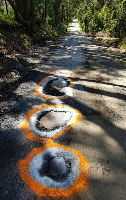 Frustrated locals in Cartons Road Gordon have grabbed their paint cans to warn drivers of multiple potholes. Picture from Facebook.