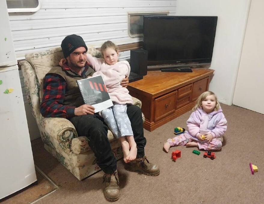 Tamara Wardlaw's fiance (holding contract) and children, aged 3 and 6, have lived through two wet years in an Avoca caravan - and the collapse of Ballarat's Bond Homes means it will continue indefinitely. Picture by Tamara Wardlaw.