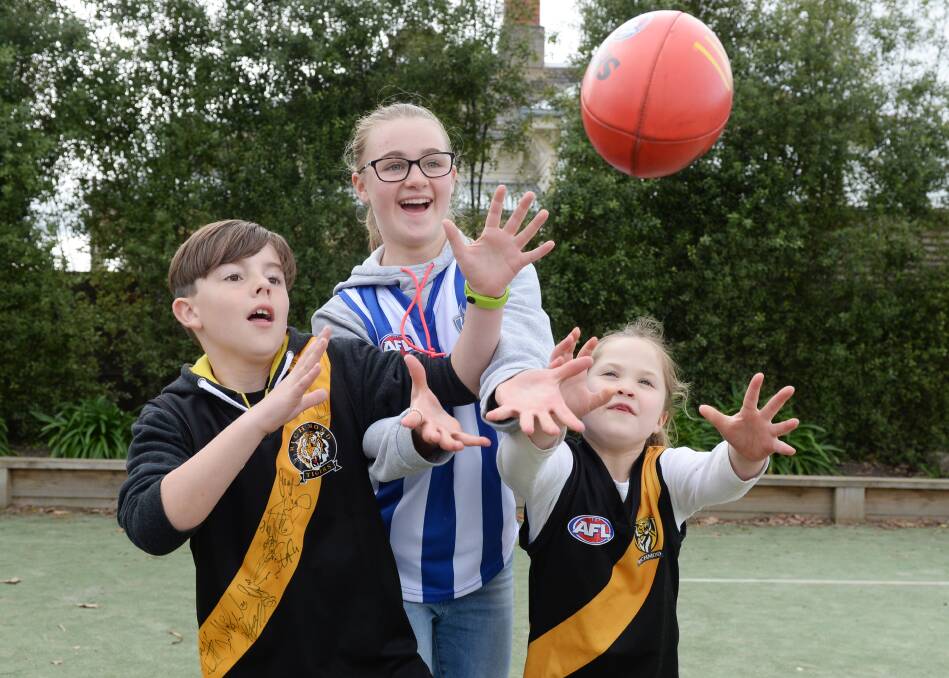 SCORE: St Patrick's Primary pupils Noah, Grade 4, Felicity, Grade 6, and Meg, Grade 1, run to mark the football. Picture: Kate Healy 