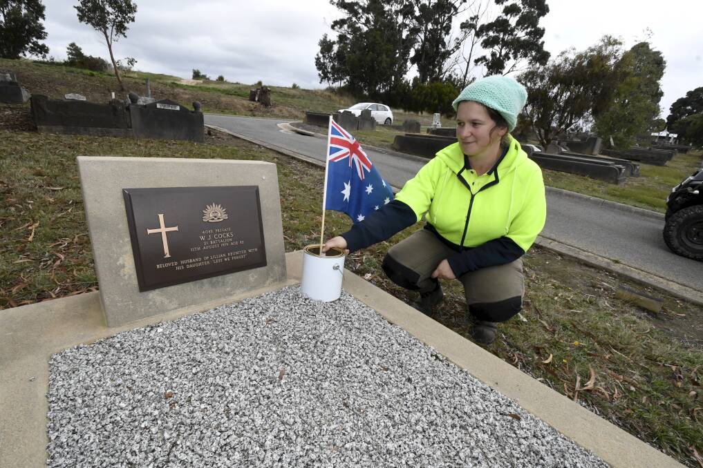 Ballarat Cemeteries' Morag McCann places an Australian flag on the grave of a serviceman ahead of Anzac Day. Picture by Lachlan Bence 