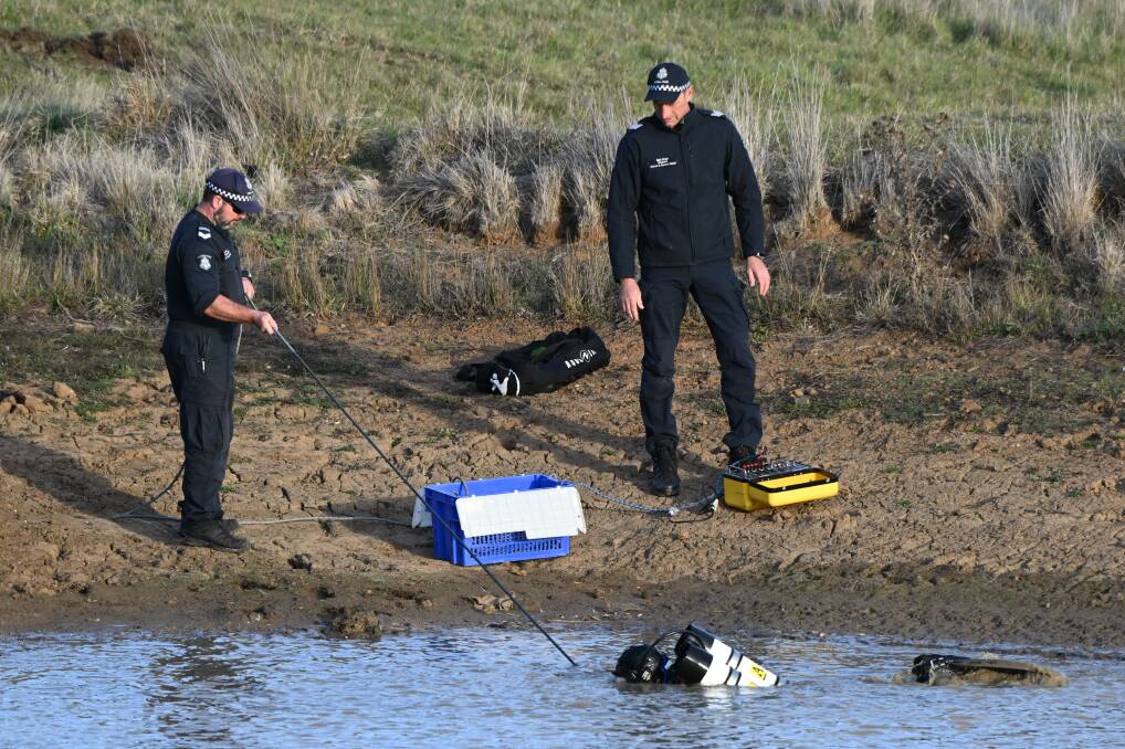 Police divers prepare to search the dam. Picture by Lachlan Bence