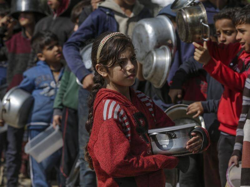 Displaced Palestinian children queue up with their pots and containers waiting to receive food. (EPA PHOTO)