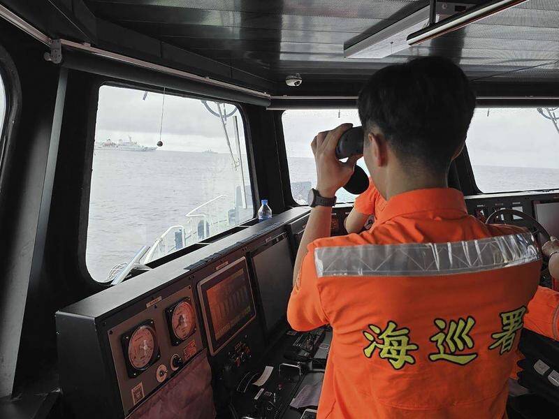 A Taiwanese Coast Guard member monitors a Chinese navy ship near the north of Taiwan. (AP PHOTO)